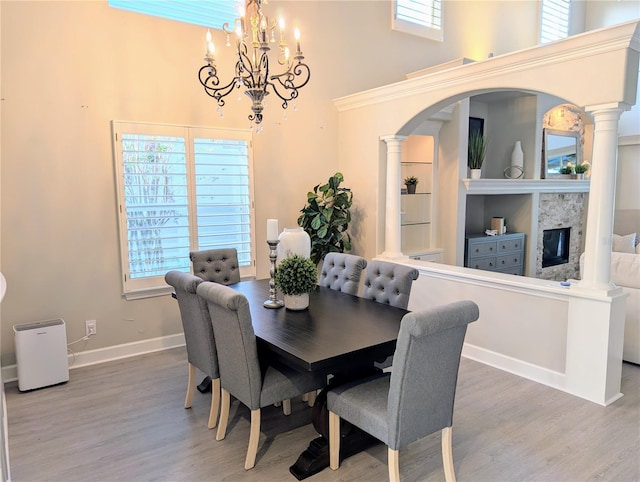 dining space featuring wood finished floors, arched walkways, a chandelier, and a towering ceiling