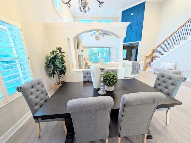 dining area with arched walkways, wood finished floors, ornate columns, and a towering ceiling