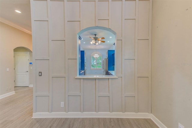 details with arched walkways, a decorative wall, freestanding refrigerator, and ceiling fan