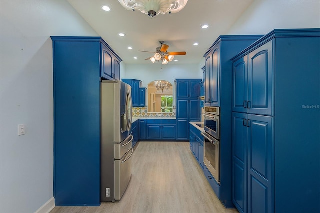 kitchen with blue cabinetry, light wood-style flooring, ceiling fan, appliances with stainless steel finishes, and backsplash