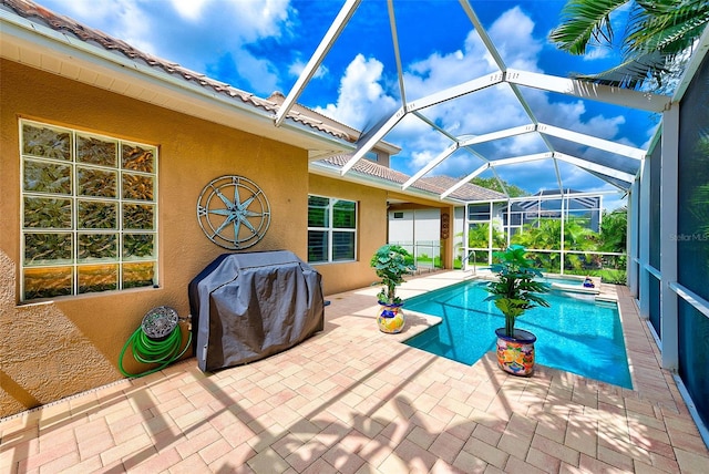 pool featuring grilling area, glass enclosure, an in ground hot tub, and a patio