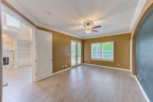 spare room with crown molding, a ceiling fan, light wood-type flooring, and a textured ceiling