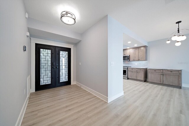 entryway with light wood-type flooring, french doors, and a chandelier