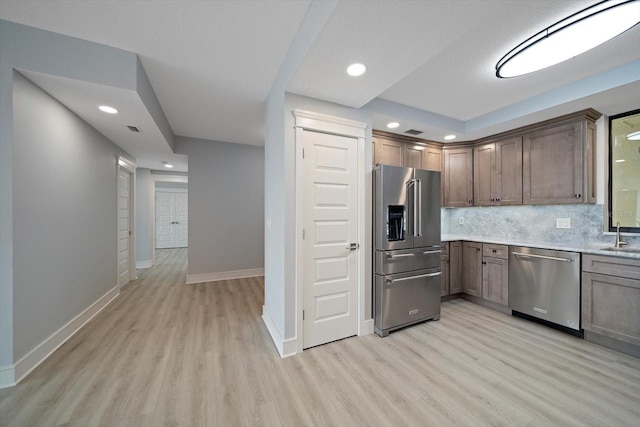 kitchen featuring light wood-type flooring, sink, appliances with stainless steel finishes, and decorative backsplash