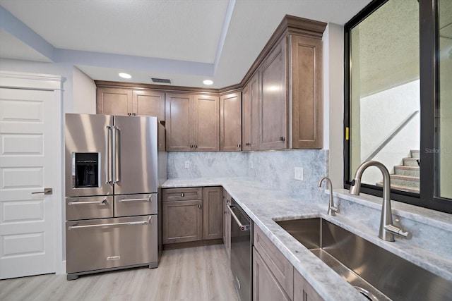 kitchen featuring light hardwood / wood-style flooring, light stone counters, stainless steel appliances, and sink