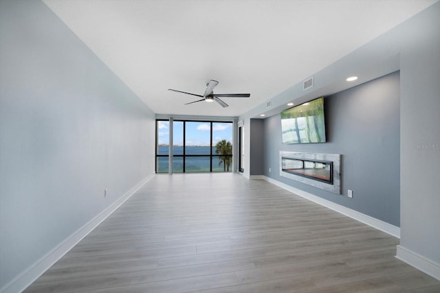 unfurnished living room featuring light wood-type flooring, floor to ceiling windows, and ceiling fan