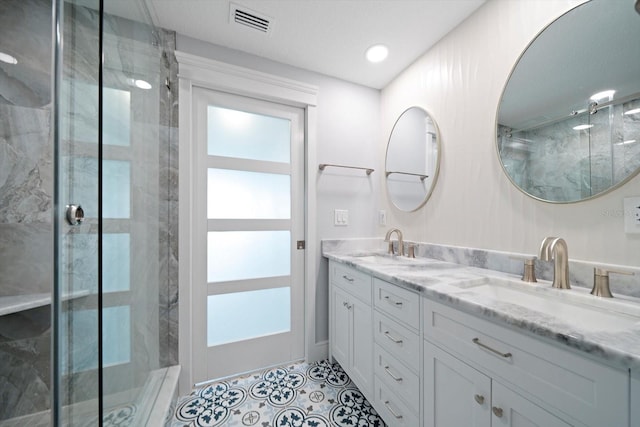 bathroom with a shower with door, vanity, and tile patterned floors