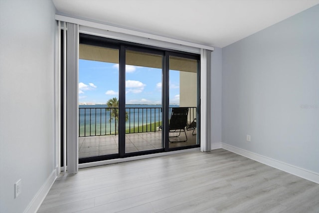 unfurnished room with a water view and light wood-type flooring