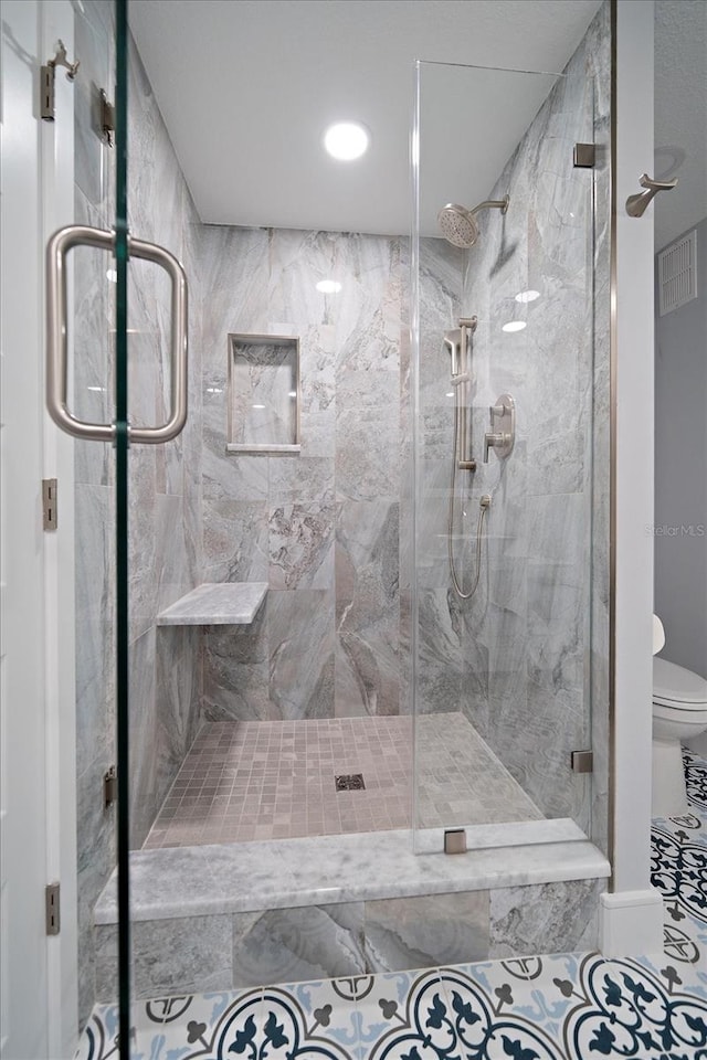 bathroom with toilet and a shower with shower door