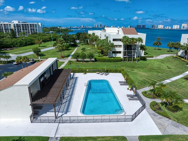 view of swimming pool with a patio area, a lawn, and a water view