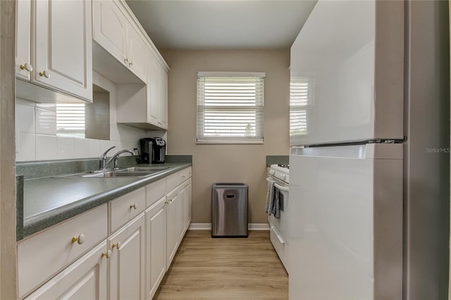 kitchen with a healthy amount of sunlight, sink, stainless steel fridge, and white range with gas cooktop