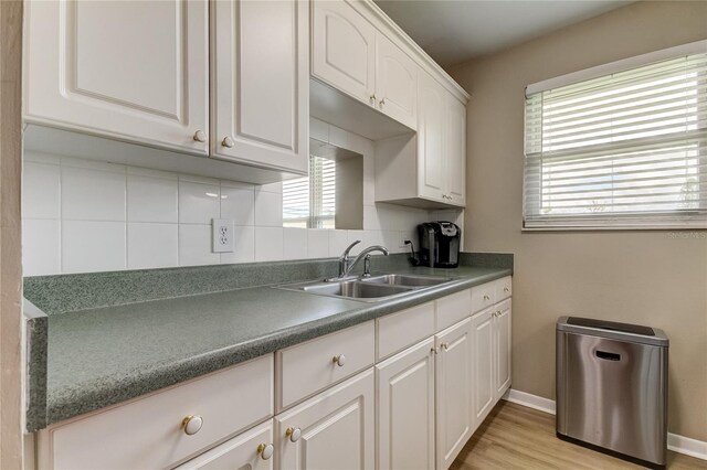 kitchen featuring backsplash, sink, white cabinetry, and light hardwood / wood-style flooring