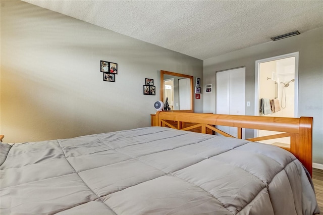 bedroom featuring ensuite bath, a textured ceiling, and a closet