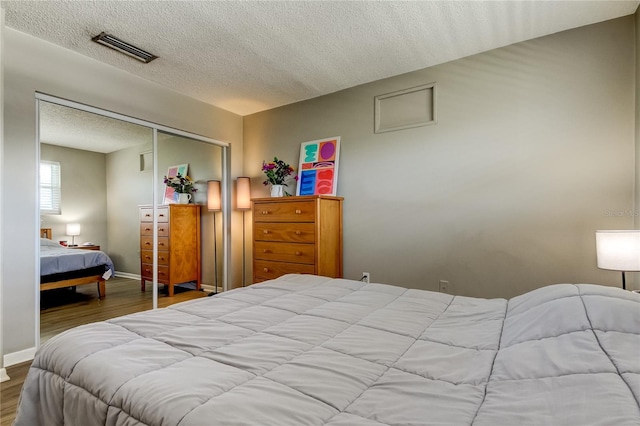 bedroom with light wood-type flooring, a textured ceiling, and a closet