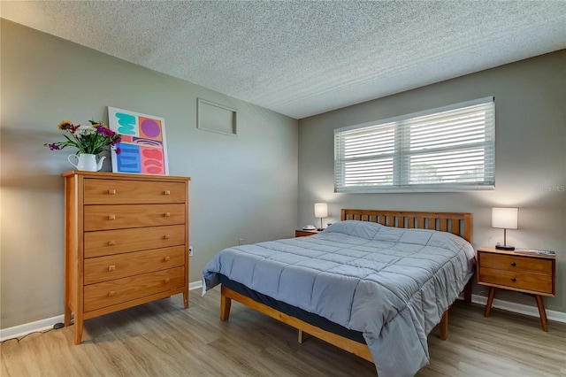 bedroom featuring a textured ceiling and light hardwood / wood-style flooring