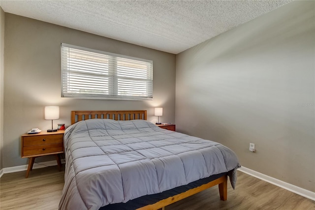 bedroom with light wood-type flooring and a textured ceiling