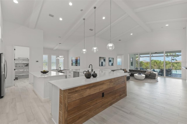 kitchen with decorative light fixtures, high vaulted ceiling, a spacious island, and a healthy amount of sunlight