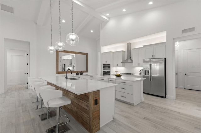 kitchen with hanging light fixtures, white cabinetry, stainless steel fridge, high vaulted ceiling, and a kitchen island