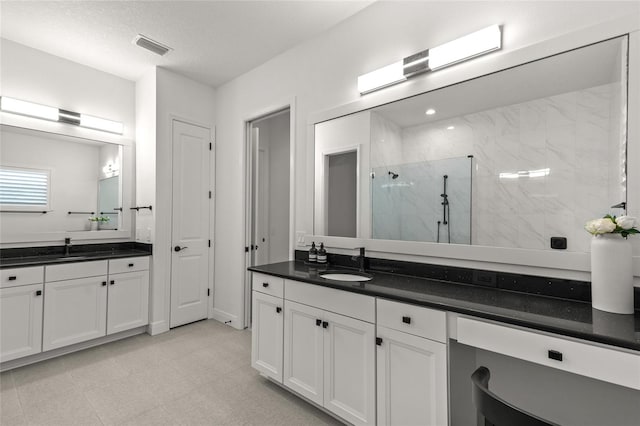 bathroom with vanity, a textured ceiling, and a tile shower