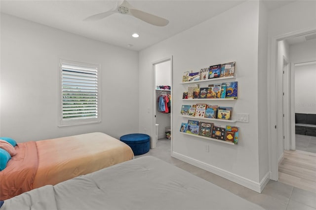 tiled bedroom featuring a spacious closet, ceiling fan, and a closet