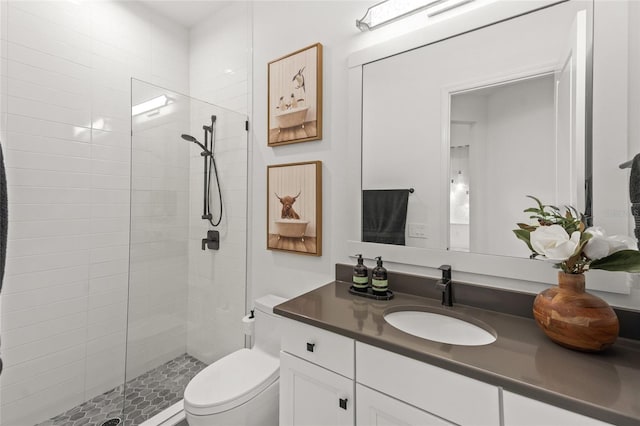 bathroom featuring vanity, toilet, and a tile shower