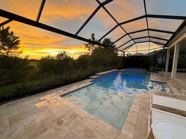 pool at dusk with a lanai and a patio area