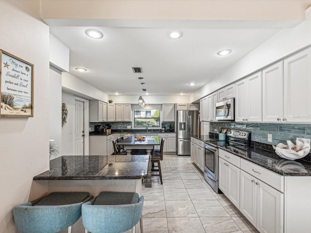 kitchen featuring a breakfast bar, appliances with stainless steel finishes, backsplash, and hanging light fixtures