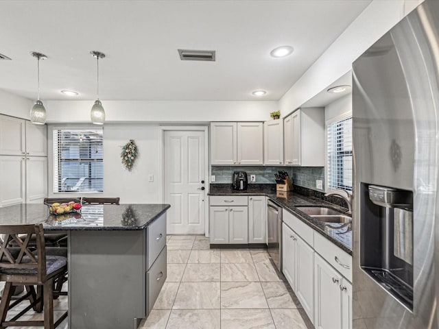 kitchen with pendant lighting, stainless steel appliances, sink, backsplash, and a breakfast bar