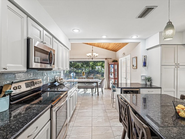 kitchen with decorative light fixtures, lofted ceiling, a notable chandelier, decorative backsplash, and stainless steel appliances