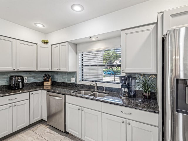 kitchen featuring stainless steel appliances, dark stone countertops, white cabinets, and sink