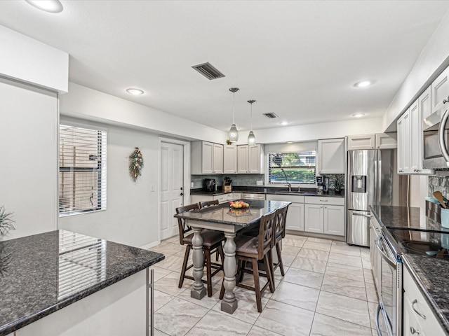 kitchen featuring appliances with stainless steel finishes, decorative backsplash, pendant lighting, a breakfast bar, and sink