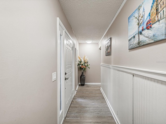 hall with wood-type flooring, crown molding, and a textured ceiling