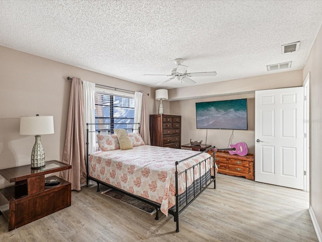 bedroom featuring ceiling fan, light hardwood / wood-style floors, and a textured ceiling