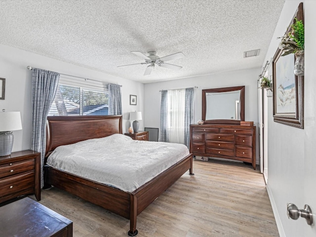 bedroom with ceiling fan, light wood-type flooring, multiple windows, and a textured ceiling