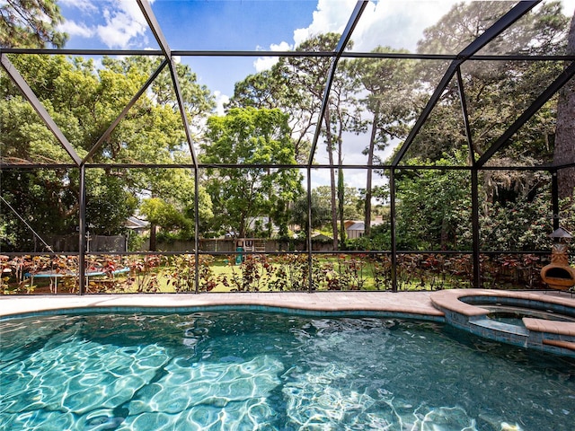 view of swimming pool featuring glass enclosure and an in ground hot tub