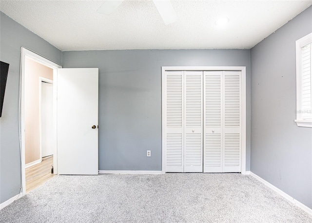 unfurnished bedroom featuring a textured ceiling, ceiling fan, a closet, and light colored carpet