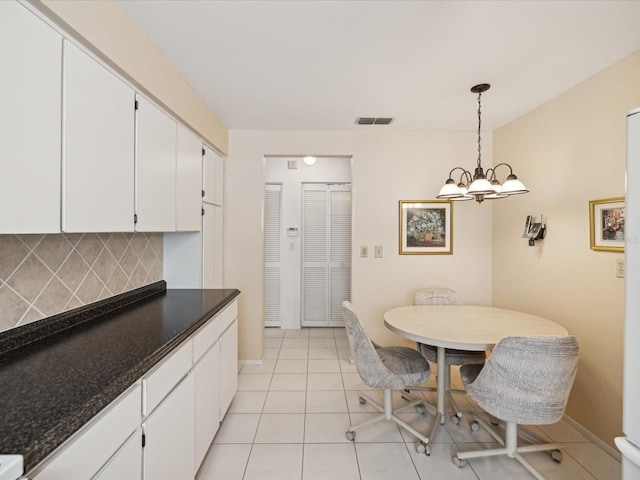 kitchen featuring light tile patterned floors, hanging light fixtures, decorative backsplash, white cabinetry, and dark stone countertops