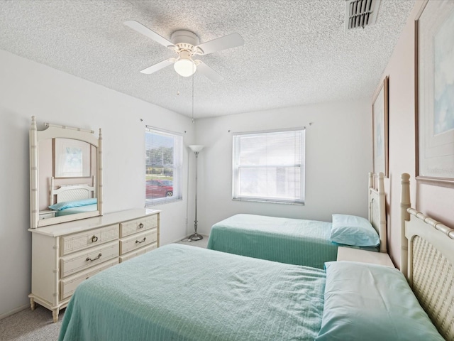 carpeted bedroom featuring ceiling fan and a textured ceiling