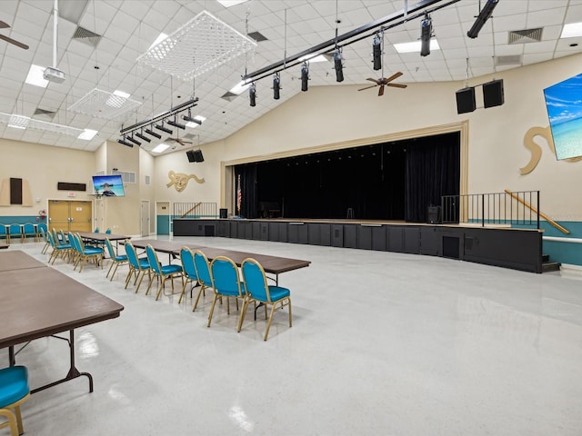 rec room with concrete flooring, ceiling fan, and a towering ceiling