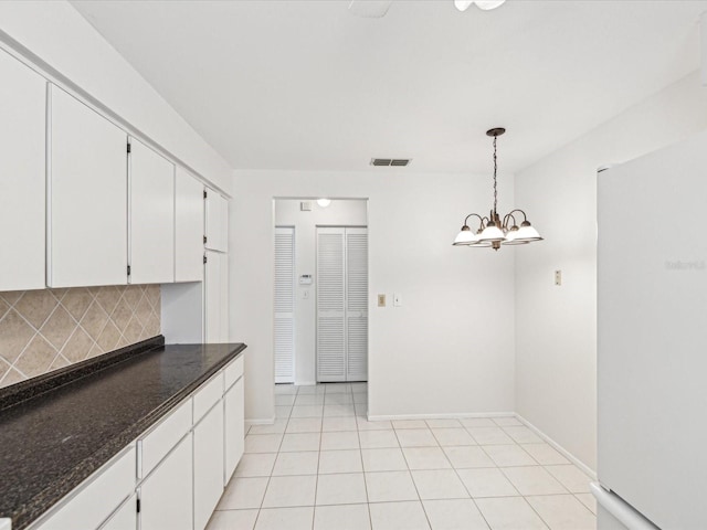 kitchen with white cabinetry, white fridge, dark stone counters, and decorative light fixtures