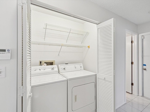 laundry area featuring separate washer and dryer, a textured ceiling, and light tile patterned floors