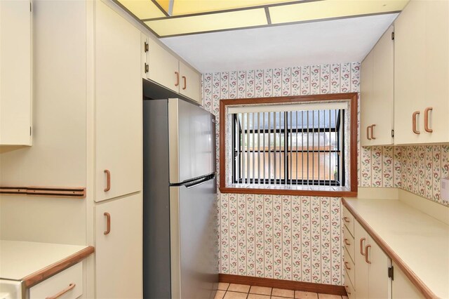 kitchen featuring stainless steel fridge, white cabinetry, and light tile patterned flooring