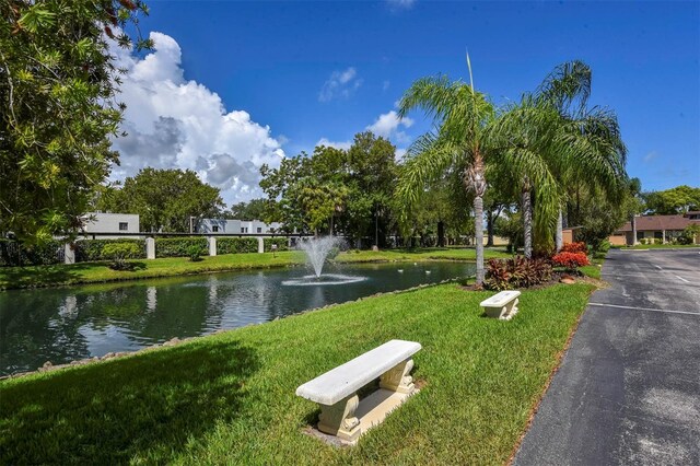 surrounding community with a water view and a yard