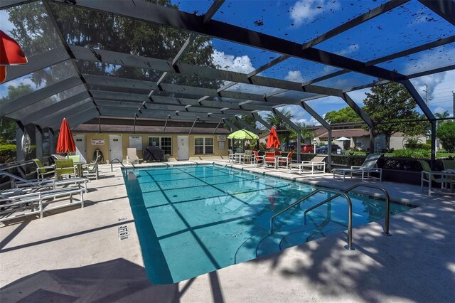 view of swimming pool featuring glass enclosure and a patio area