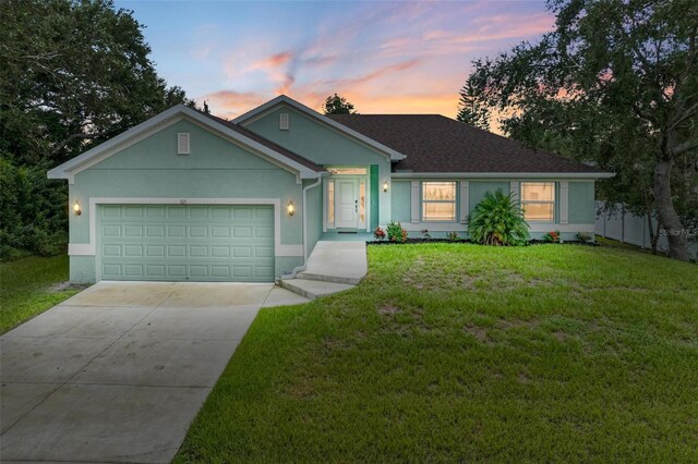 ranch-style house with a garage and a lawn