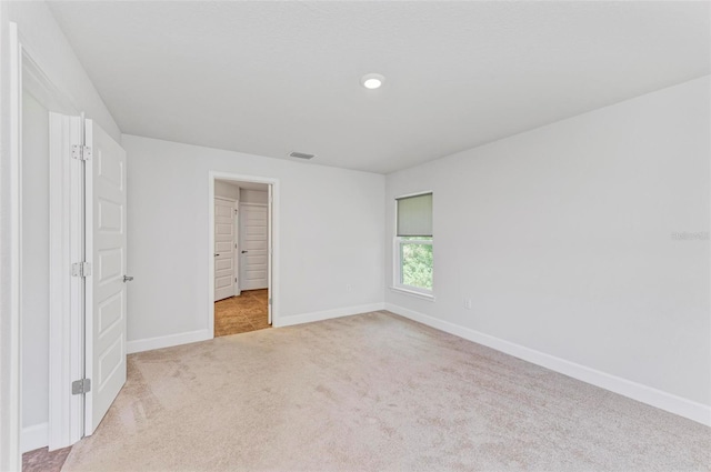 unfurnished bedroom featuring a closet, light colored carpet, and a walk in closet