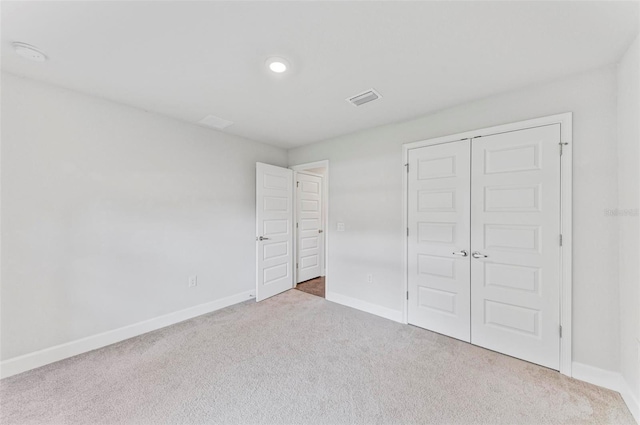 unfurnished bedroom with a closet and light colored carpet