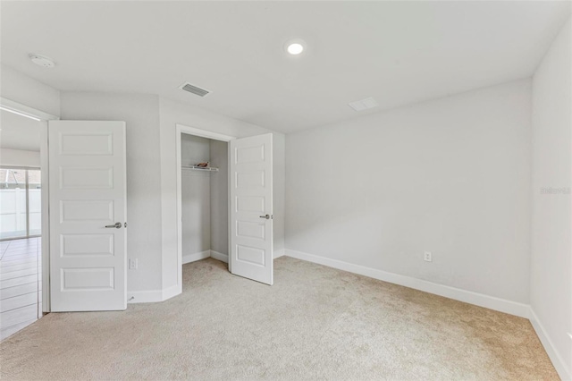 unfurnished bedroom with a closet and light colored carpet