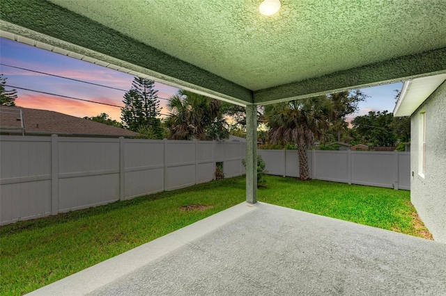 patio terrace at dusk featuring a yard