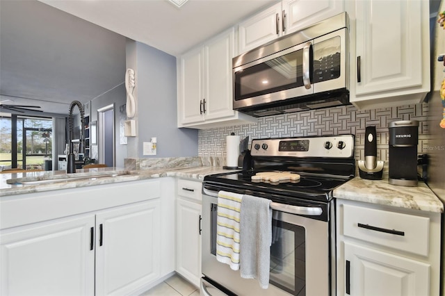 kitchen with appliances with stainless steel finishes, light stone countertops, white cabinetry, and sink